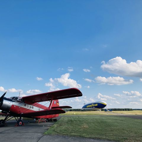 Roter Doppeldecker mit Zeppelin im Hintergrund auf dem Flugplatz in Strausberg
