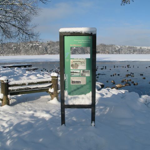 Seesichtenwanderweg in Strausberg im Winter mit einem Infoschild vor dem Straussee
